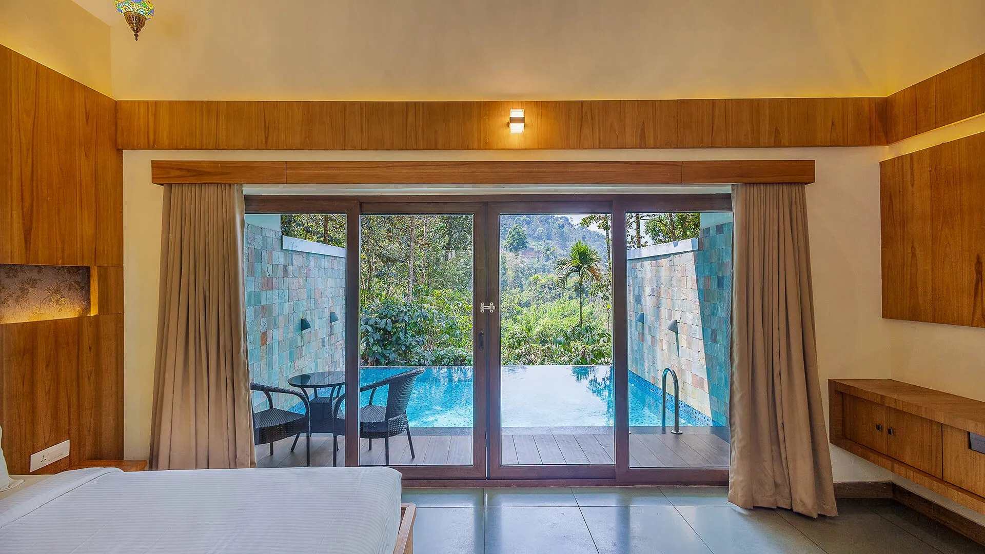 Bedroom opening onto a private infinity pool with mountain views at Karma Vythiri