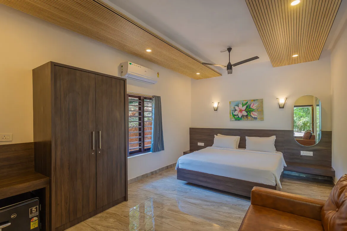 Hotel Unit Deluxe bedroom with wood-panel headboard and mirror, Karma Vythiri