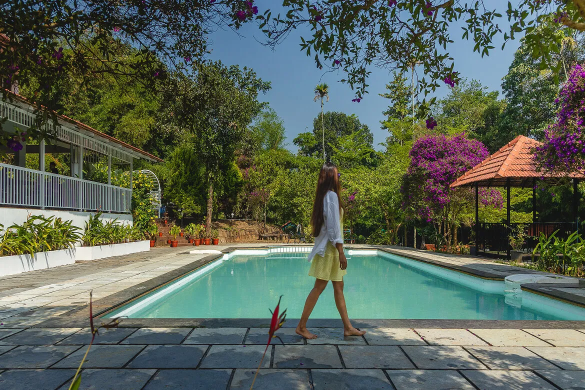Guest strolling by the swimming pool at Karma Vythiri, with garden and gazebo views
