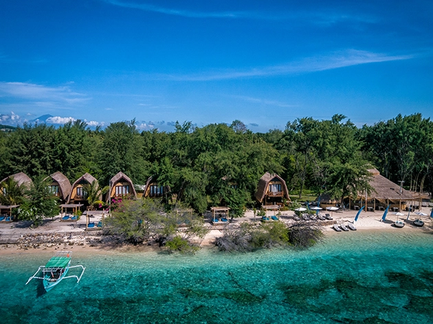 Aerial view of thatched-roof beach bungalows at a Karma Retreats property