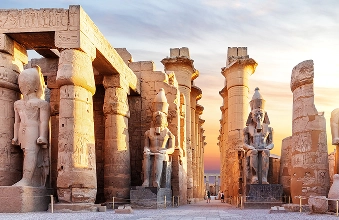 Pharaoh statues and columns at Luxor Temple at sunset