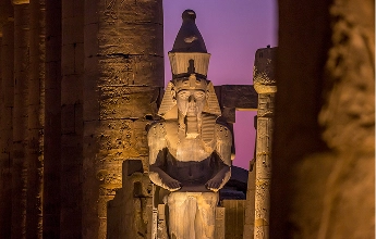 Illuminated pharaoh statue at Luxor Temple at night