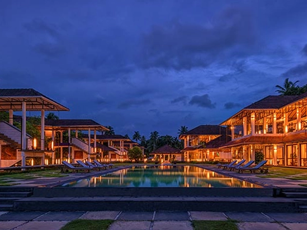 Resort pool and buildings illuminated at dusk, a Karma Royal property