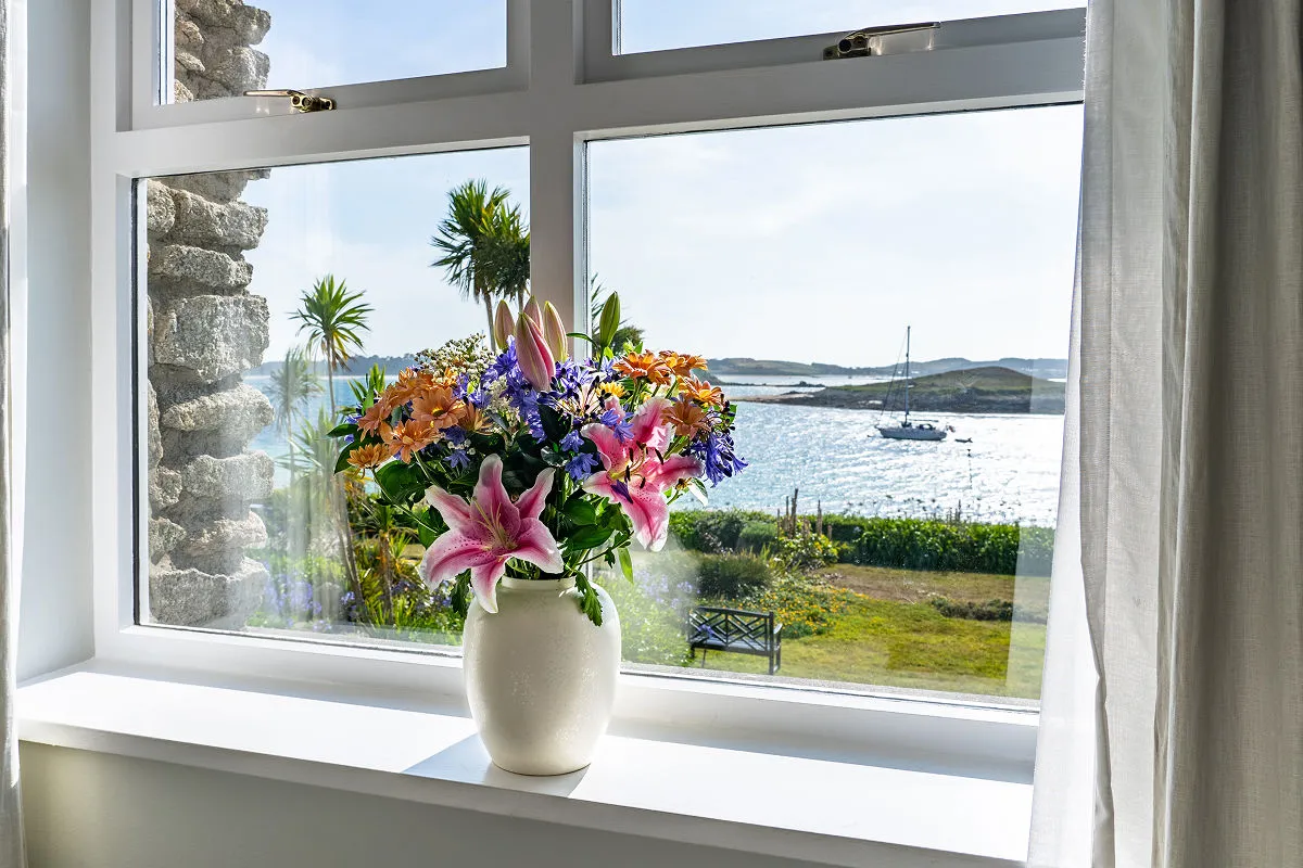 Window view from Karma St. Martin's over gardens and the sea to a sailing boat, Isles of Scilly