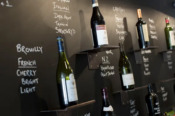 Chalkboard wine wall with bottles and handwritten tasting notes in the Bar & Wine Lounge at Karma St. Martin's
