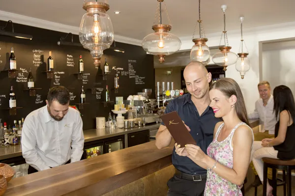 Couple browsing the drinks menu at the bar in the Bar & Wine Lounge, Karma St. Martin's