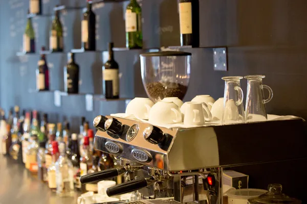 Espresso machine with coffee cups and a wine wall behind the bar in the Bar & Wine Lounge, Karma St. Martin's