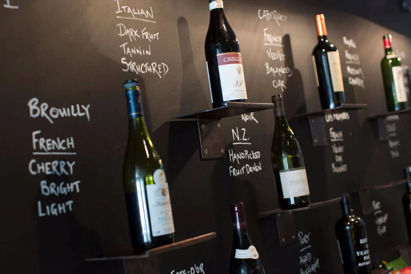Chalkboard wine wall with bottles and handwritten tasting notes in the Bar & Wine Lounge at Karma St. Martin's