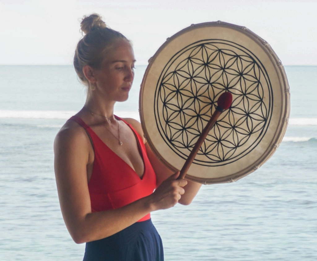 Sound healing ceremony with traditional frame drum on the beach, part of Karma Curates