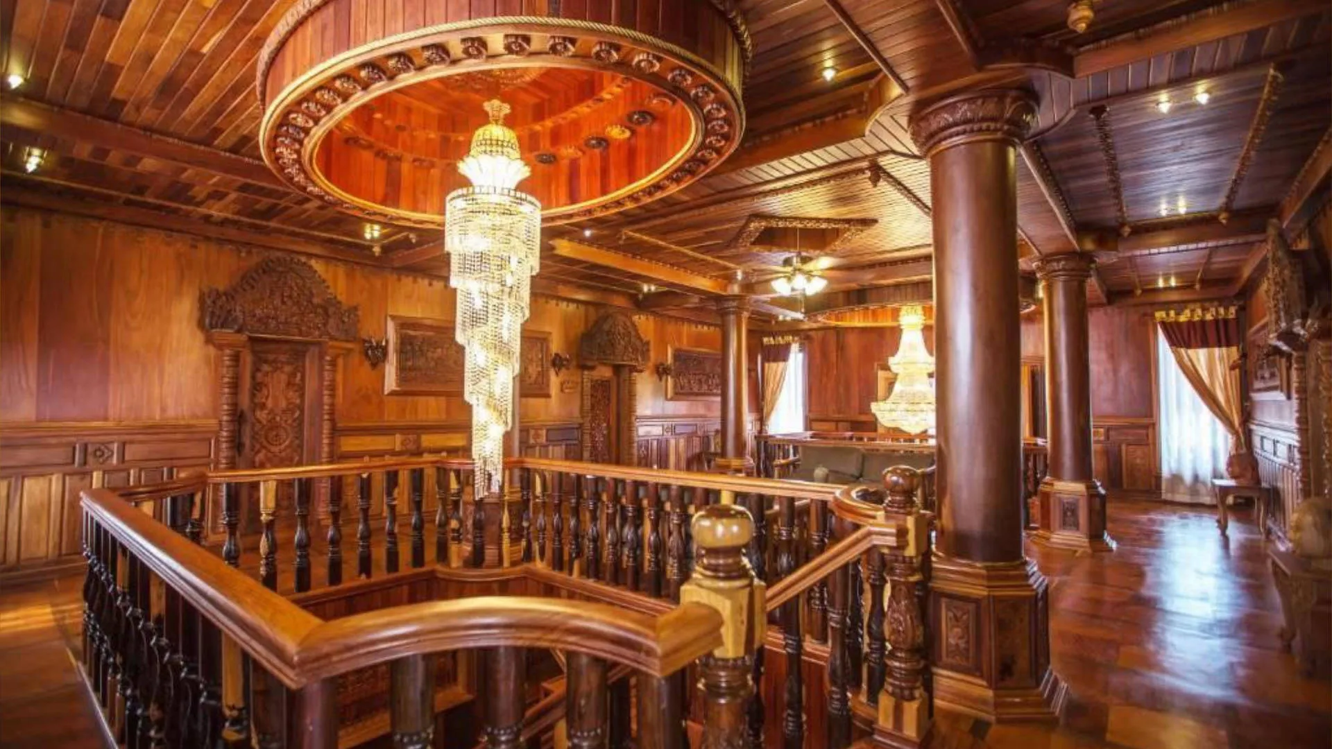 Grand wooden interior with carved staircase and crystal chandeliers at Karma Bayon