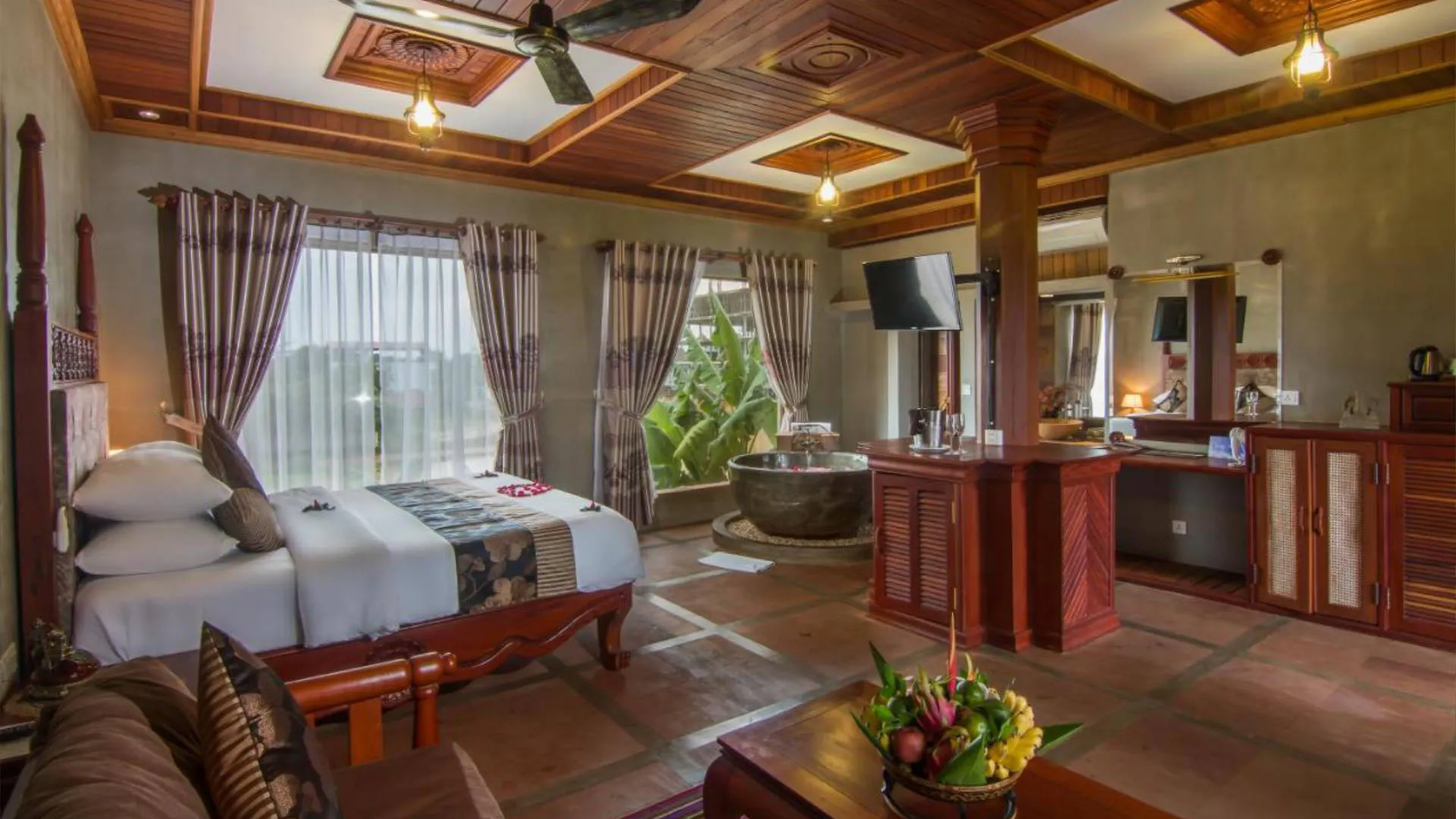 Spacious guest room with four-poster bed and stone soaking tub at Karma Bayon